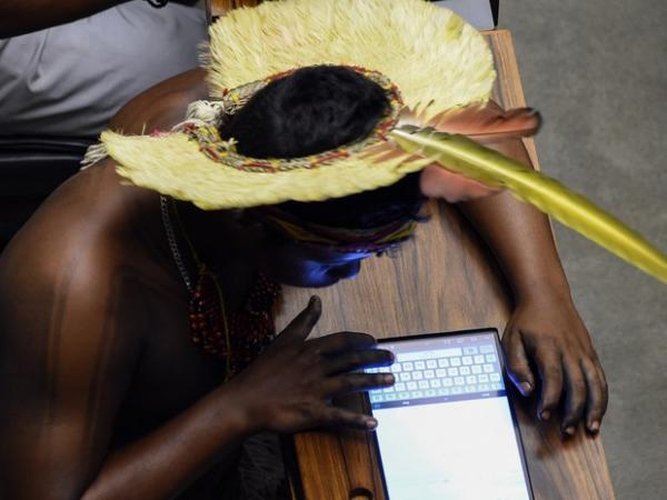 Um índio utiliza um tablet durante sessão especial em homenagem aos povos indígenas no Congresso Nacional, em Brasília. Os índios presentes no plenário protestaram contra PEC que altera demarcação de terras (Foto: Evaristo Sa/AFP)